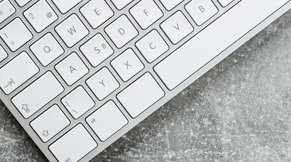 Clavier blanc sur fond gris texturé. Les touches sont carrées avec des lettres noires.