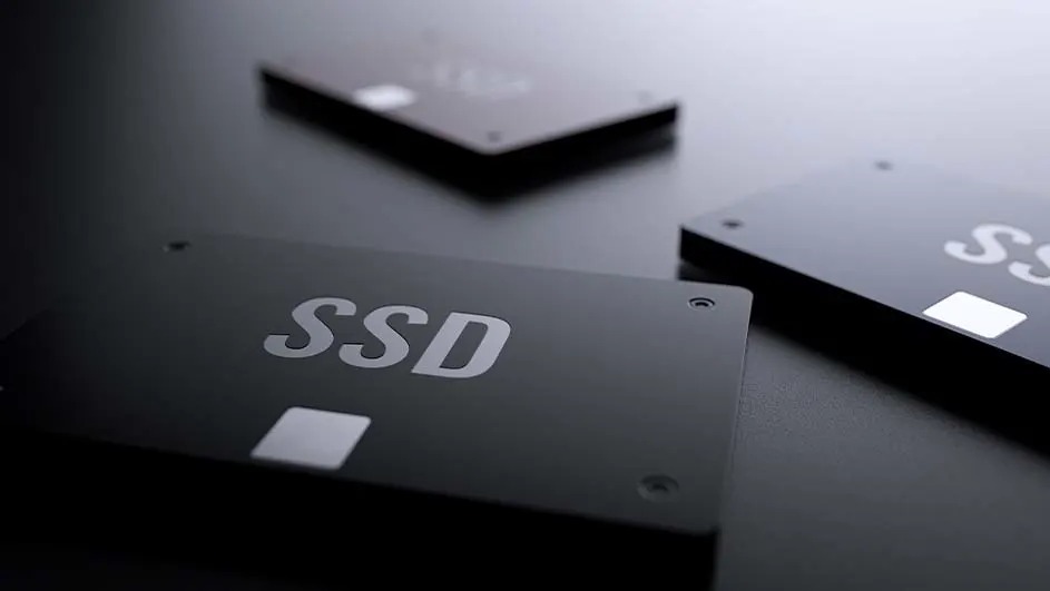 Drie zwarte SSD's liggen op een donkere ondergrond, met 'SSD' en 'SS' in witte letters erop.