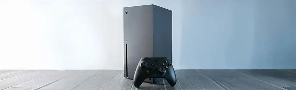 Une console de jeu noire au design épuré est positionnée verticalement, accompagnée d’une manette noire, sur un fond clair.