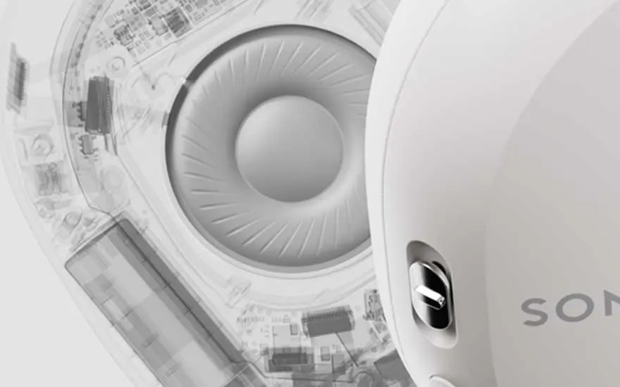 Vue rapprochée d'un casque audio blanc, montrant le haut-parleur interne et les composants électroniques.