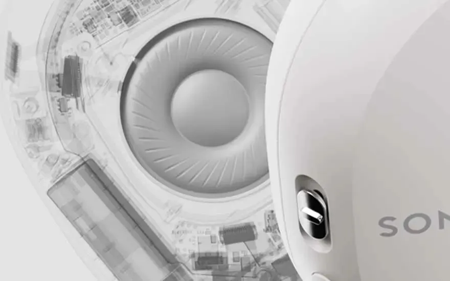 Vue rapprochée d'un casque audio blanc, montrant le haut-parleur interne et les composants électroniques.