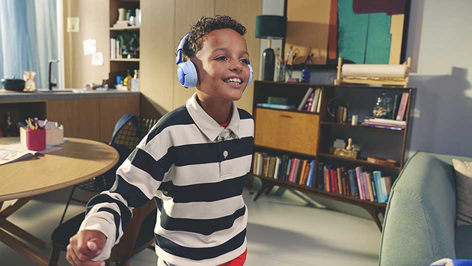 Un garçon avec un casque bleu dans une pièce avec une table ronde et une bibliothèque pleine de livres.