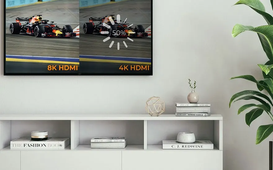 Téléviseur affichant des voitures de course en 8K et 4K, sur un meuble blanc avec des livres et une plante.