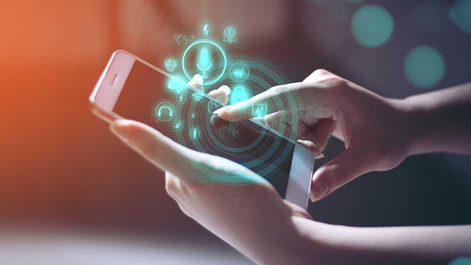 Mains tenant un smartphone blanc, avec un affichage d'icônes bleues. Le fond est flou avec des lumières.