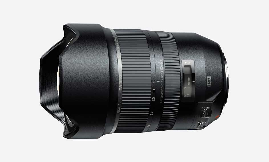 Zwarte Tamron zoomlens met ribbels en schuifregelaars, liggend op een witte achtergrond.