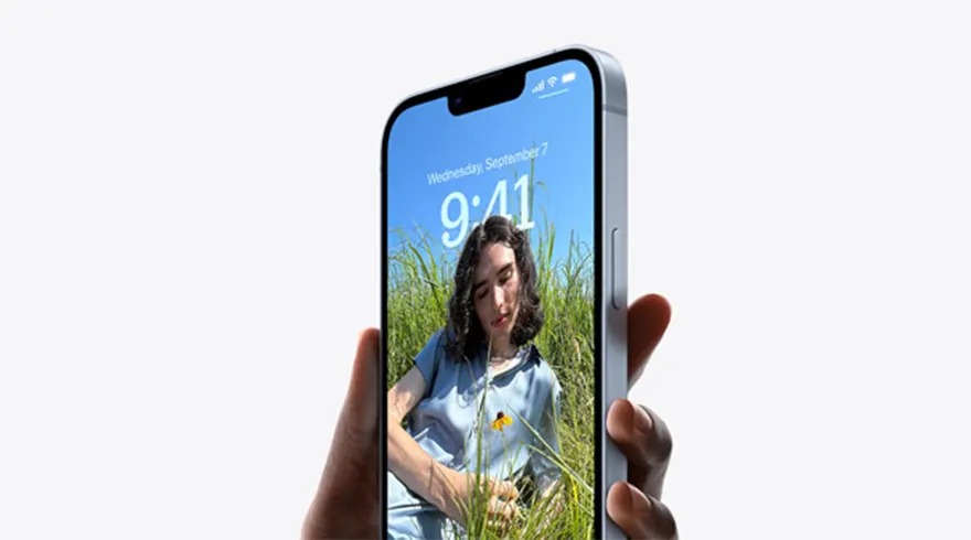 Un téléphone argenté affiche l'heure 9:41 et une photo d'une prairie sous un ciel bleu, tenu par une main sur fond blanc.