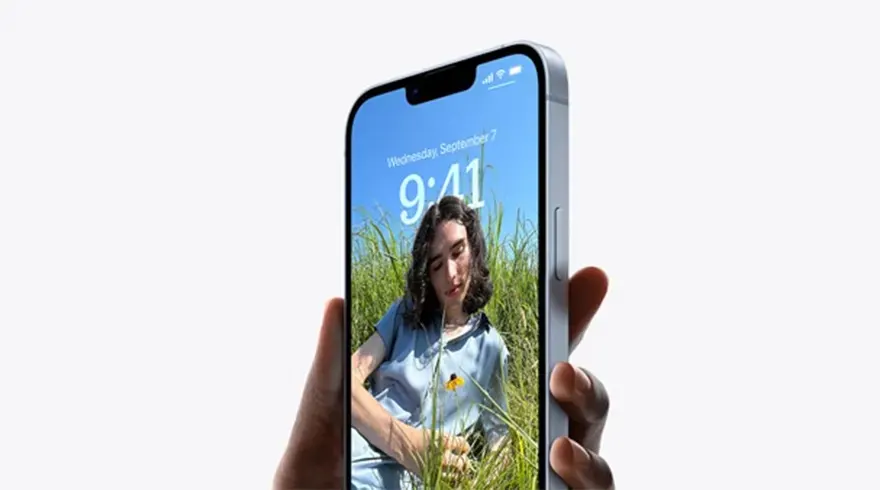 Un téléphone argenté affiche l'heure 9:41 et une photo d'une prairie sous un ciel bleu, tenu par une main sur fond blanc.