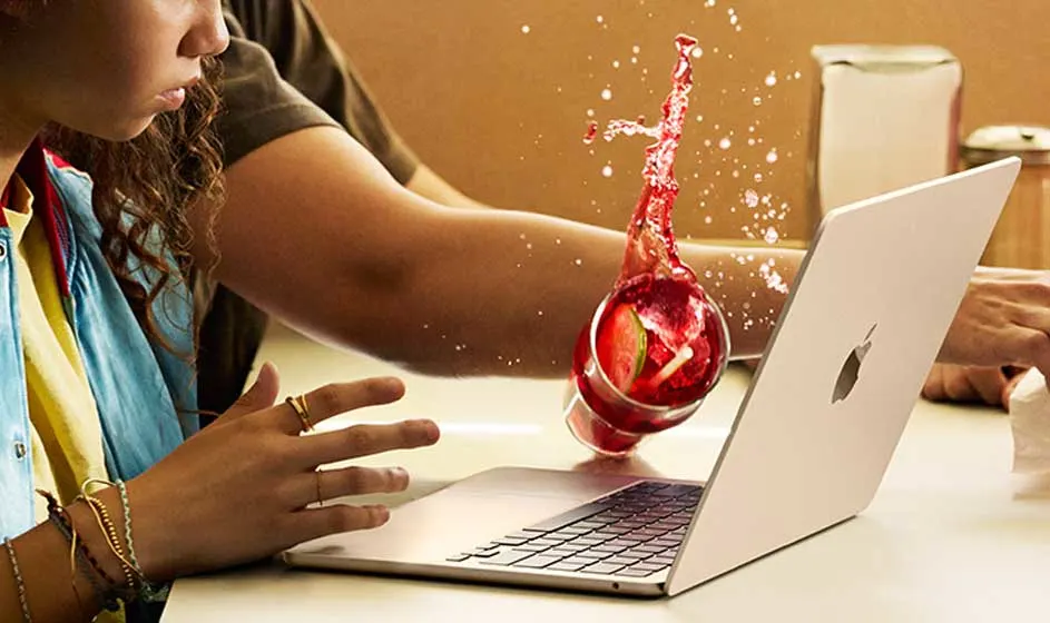 Une femme travaille sur un ordinateur portable lorsqu’une boisson rouge se renverse et éclabousse l’air. Ses mains tentent d’arrêter le liquide.