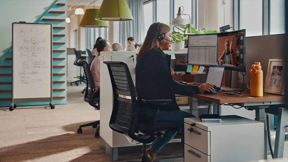 Bureau moderne avec ordinateur, plantes et lumière naturelle. Un tableau blanc est visible à l'arrière-plan.