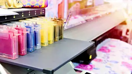 Gros plan d'une imprimante grand format avec des cartouches d'encre roses, bleues, jaunes et grises.