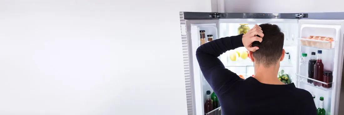 Openstaande koelkast vol drank, eieren en groenten tegen een witte achtergrond.