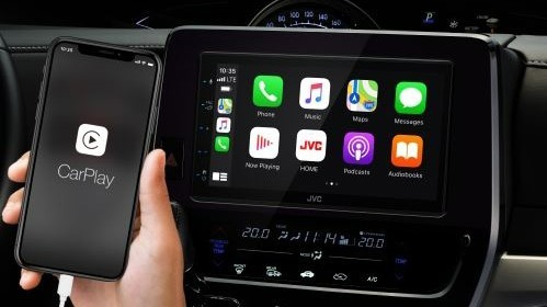 Zwarte smartphone met CarPlay-logo verbonden met auto-infotainmentsysteem met apps.