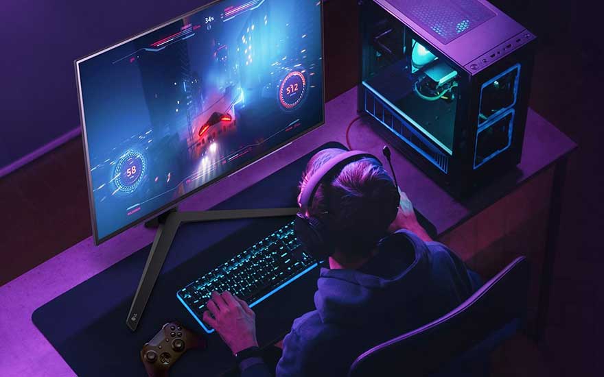 Zijaanzicht van een bureau met een computer, toetsenbord, muis en gaming pc. De kamer is verlicht met paars licht.