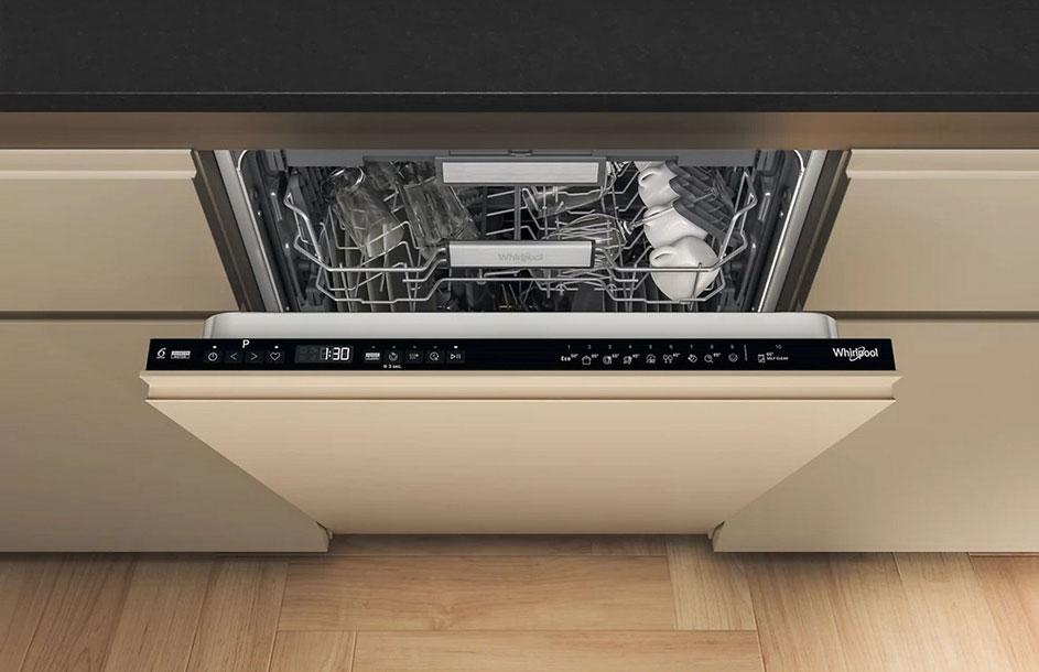 Openstaande vaatwasser met rekken vol vaatwerk, ingebouwd in een crèmekleurige keukenkast, met houten vloer en zwarte accenten.