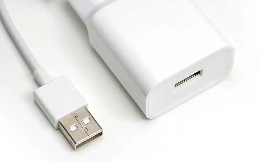 Chargeur mural blanc avec un connecteur USB sur une surface blanche.
