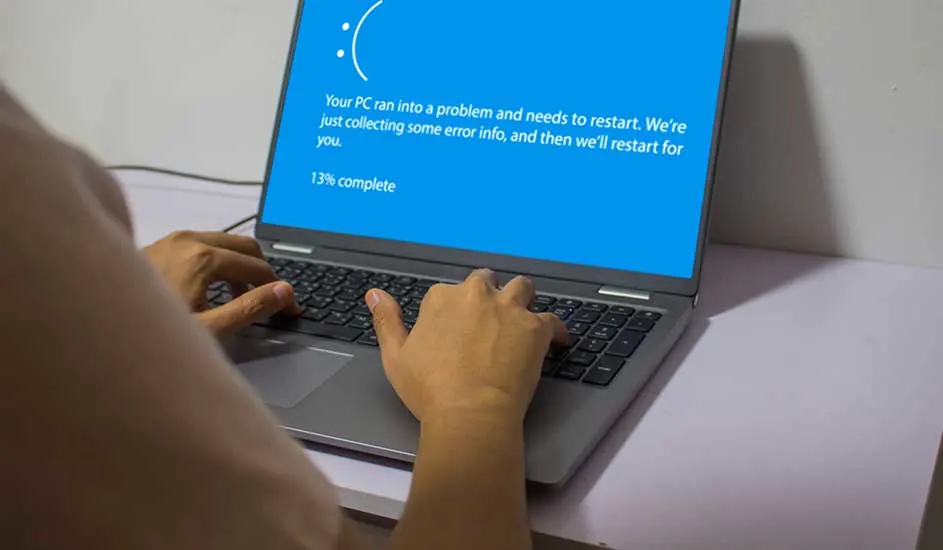 Een laptop geeft een blauw scherm met een foutmelding "Uw pc heeft een probleem en moet opnieuw worden opgestart". De voortgang is 13%.