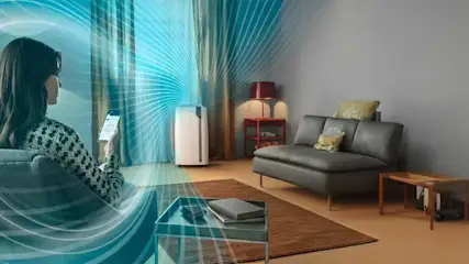 Salon avec canapé gris, table basse, purificateur d'air blanc et rideaux rayés bleus. Lignes bleues illustrant le flux d'air.