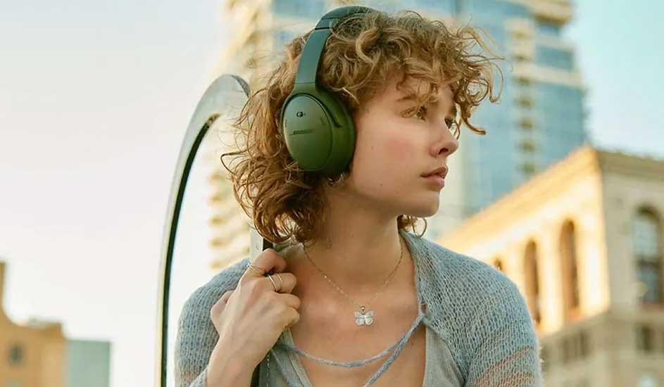 Een foto van groene koptelefoon, een zilveren ketting en gebouwen op de achtergrond.