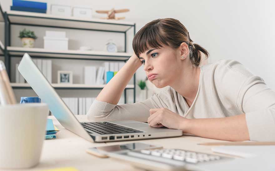 Une table avec un ordinateur portable ouvert, un clavier séparé, un pot à crayons blanc et une étagère en arrière-plan.