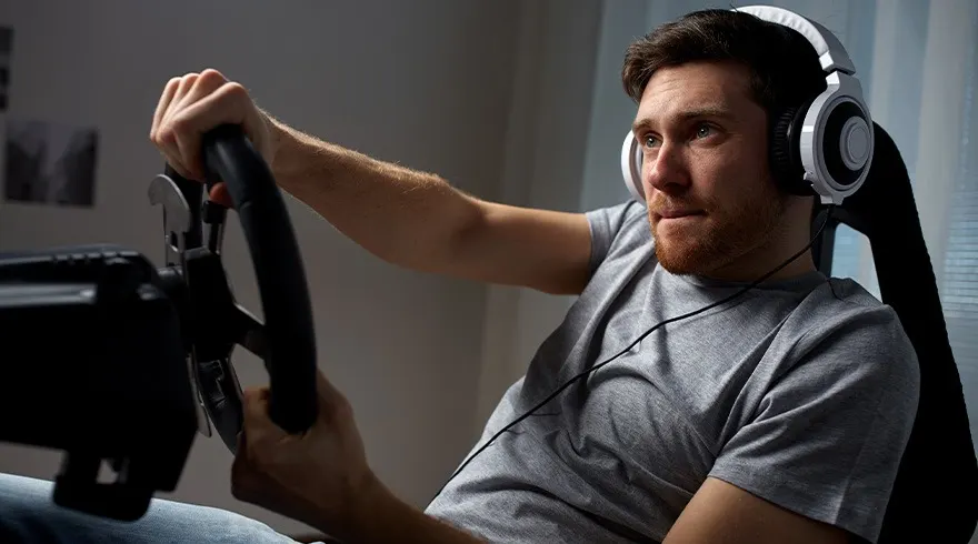 Een zwart stuur met metalen peddels wordt vastgehouden door handen, met een grijze muur op de achtergrond.