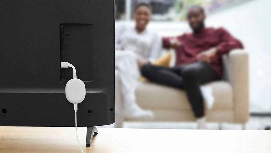 Zwarte tv met witte Chromecast-adapter. Op de achtergrond een beige zetel.