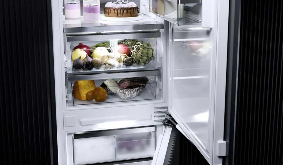 Een open koelkast met fruit, groenten, kaas, vleeswaren en desserts op de planken. De buitenkant is zwart.