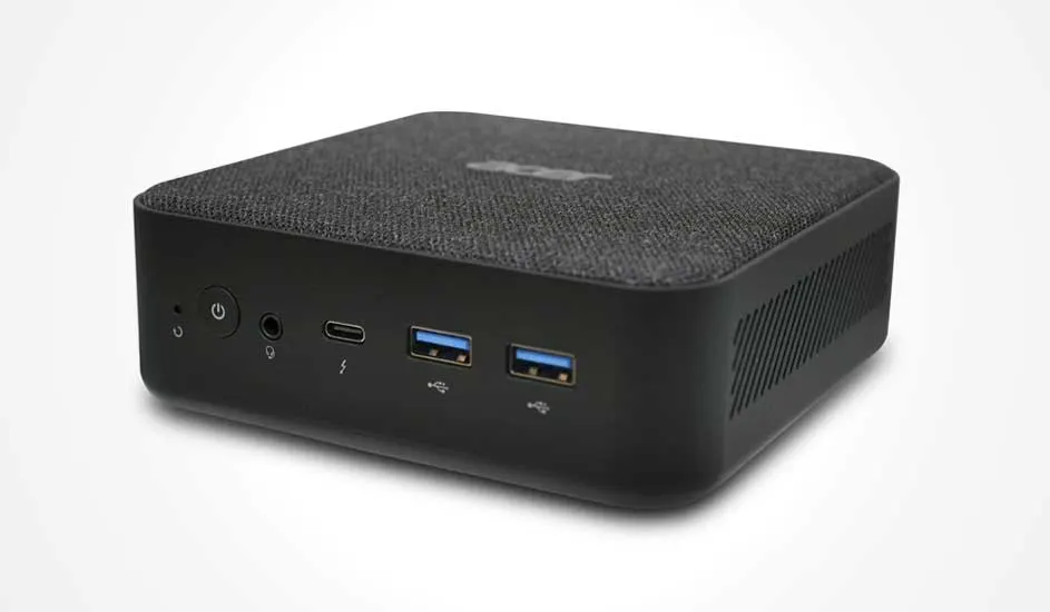 Un mini-PC noir compact avec un dessus en tissu et plusieurs ports à l’avant, dont USB et audio.