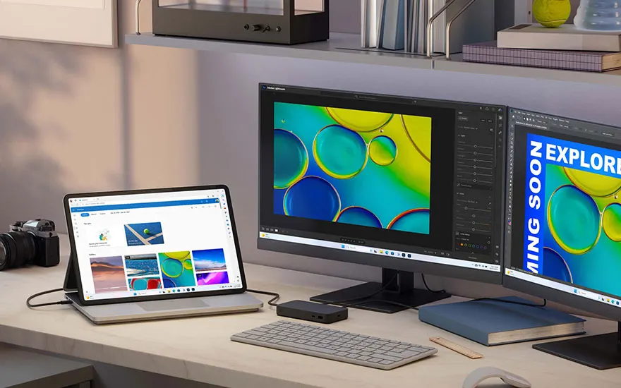 Bureau met laptop, twee monitoren, toetsenbord en camera. Monitoren tonen blauw-gele cirkelbeelden.