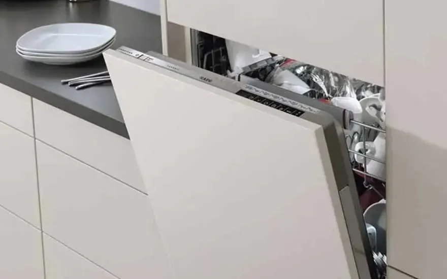 Een open AEG inbouwvaatwasser vol schone vaat staat in een moderne witte keuken, met borden en bestek op het aanrecht.