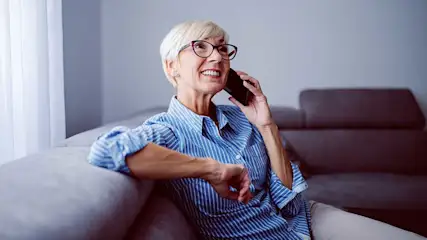 A woman sits on a sofa, having a relaxed phone call.