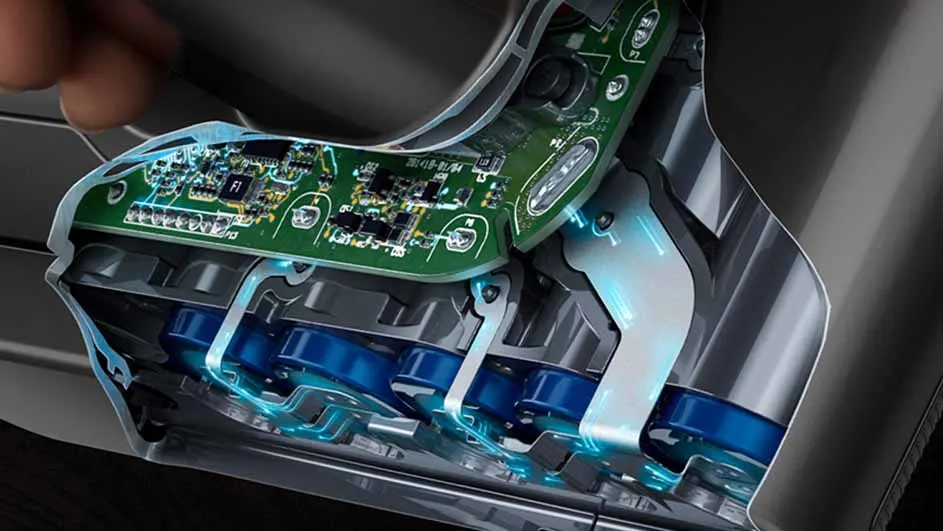 Vue rapprochée d'un appareil avec carte de circuit vert et batteries bleues, intérieur gris.