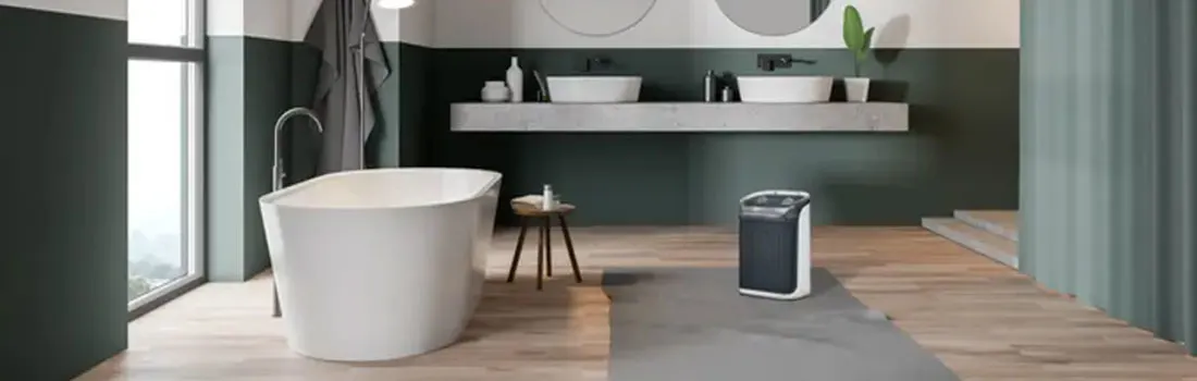 Salle de bain verte et blanche avec baignoire, lavabos, tabouret en bois et purificateur d'air sur plancher en bois.