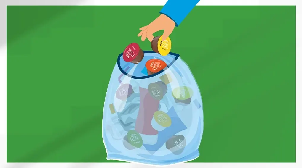 Une main jette des capsules de café colorées dans un sac transparent rempli de capsules usagées, sur fond vert.