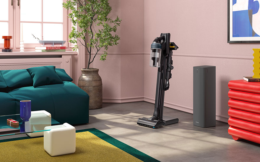 Salon rose avec canapé turquoise, plante en pot, aspirateur noir, Enceinte gris et commode rouge.