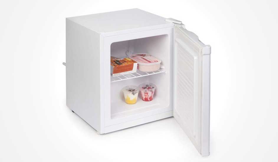 Een kleine witte vriezer met open deur, binnenin een draadrek met diepvriesmaaltijden, ijs en twee bekers dessert op de bodem.