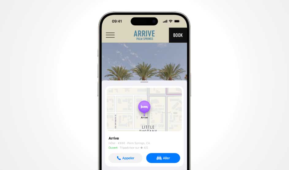 An Apple iPhone displays a hotel page with a map card and booking buttons; the Dynamic Island and slim bezels frame the clean, bright screen.