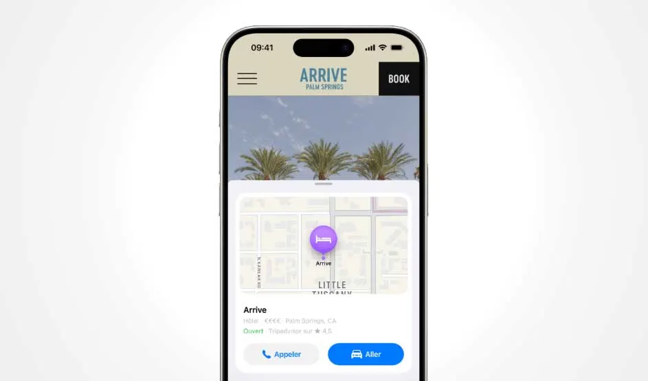An Apple iPhone displays a hotel page with a map card and booking buttons; the Dynamic Island and slim bezels frame the clean, bright screen.