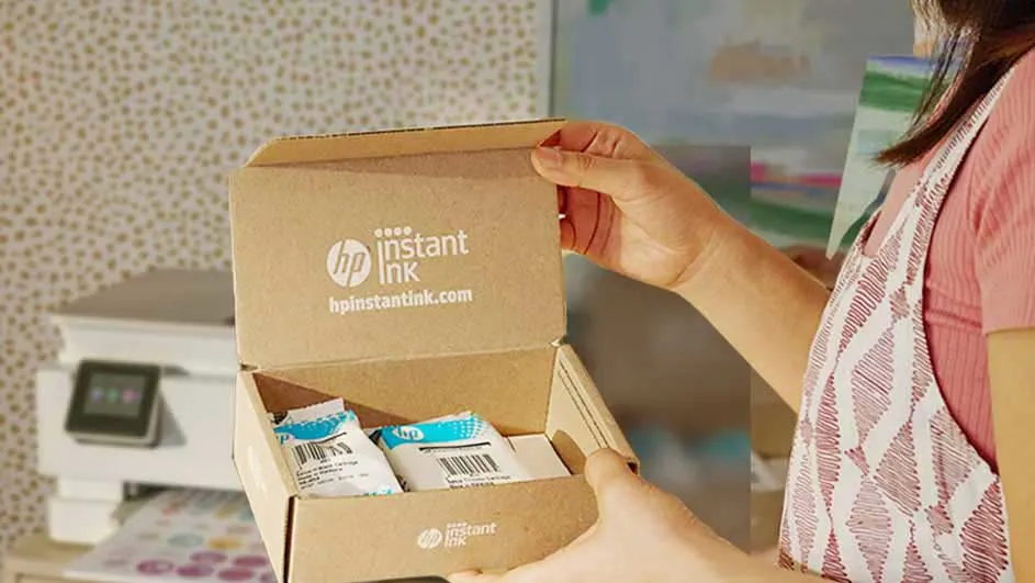 Une boîte brune ouverte "HP Instant Ink" avec des cartouches est tenue. Une imprimante blanche est visible en arrière-plan.