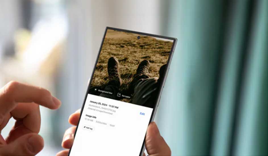 Un smartphone affiche une photo de chaussures sur un terrain herbeux. Des mains tiennent le téléphone devant un rideau bleu.