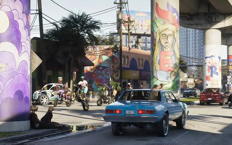 A lively street beneath a bridge, covered in vibrant murals, with bikers and cars weaving between painted columns.