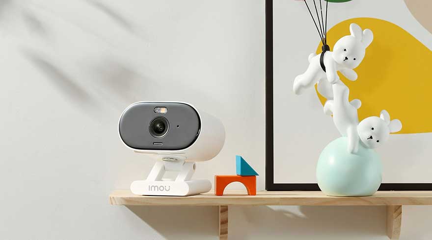 Caméra grise et blanche sur étagère en bois, avec des blocs colorés et une décoration murale abstraite.