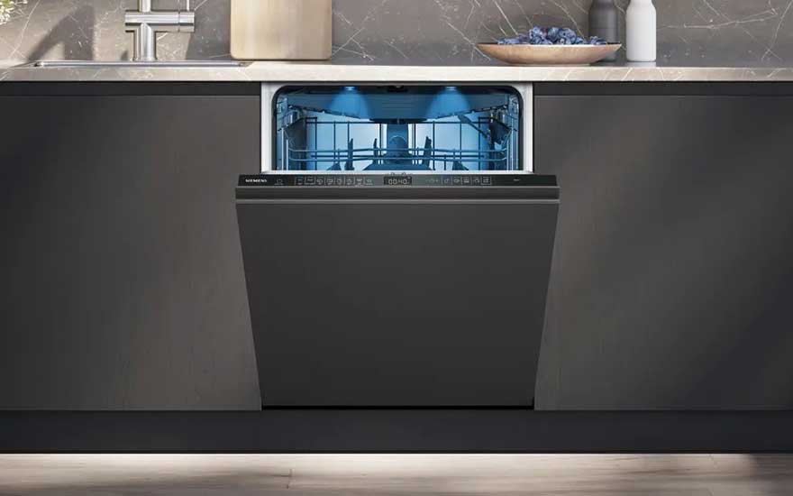 Un lave-vaisselle moderne à demi-ouvert avec éclairage intérieur bleu est intégré dans une cuisine élégante et plan de travail sombre.