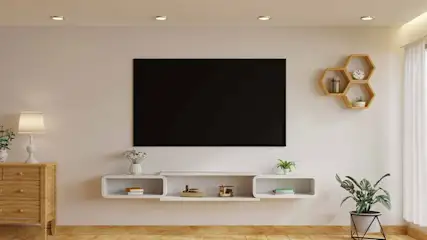 Salon avec TV noire, meuble TV blanc, étagères hexagonales en bois, parquet clair et rideaux blancs.