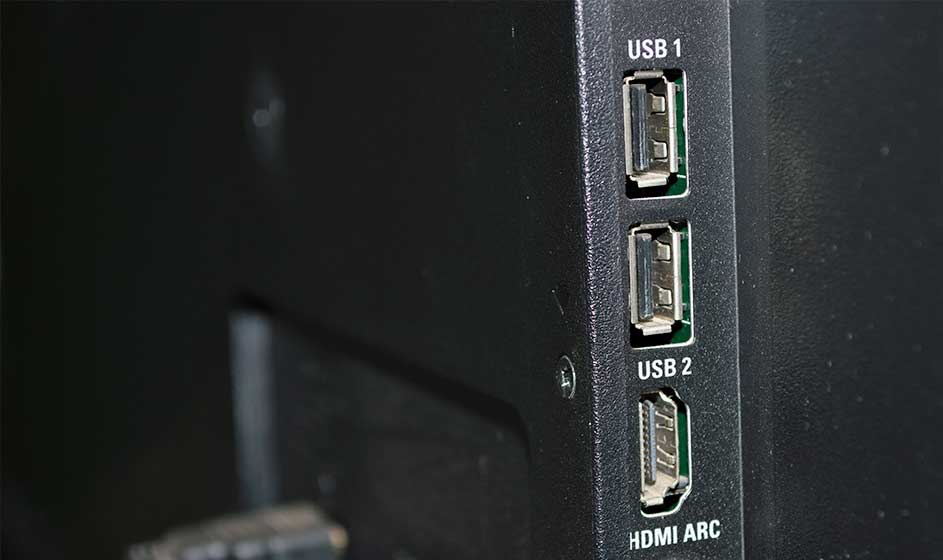 Een zwart toestel toont twee USB-poorten en een HDMI ARC-aansluiting in close-up, tegen een donkere achtergrond.