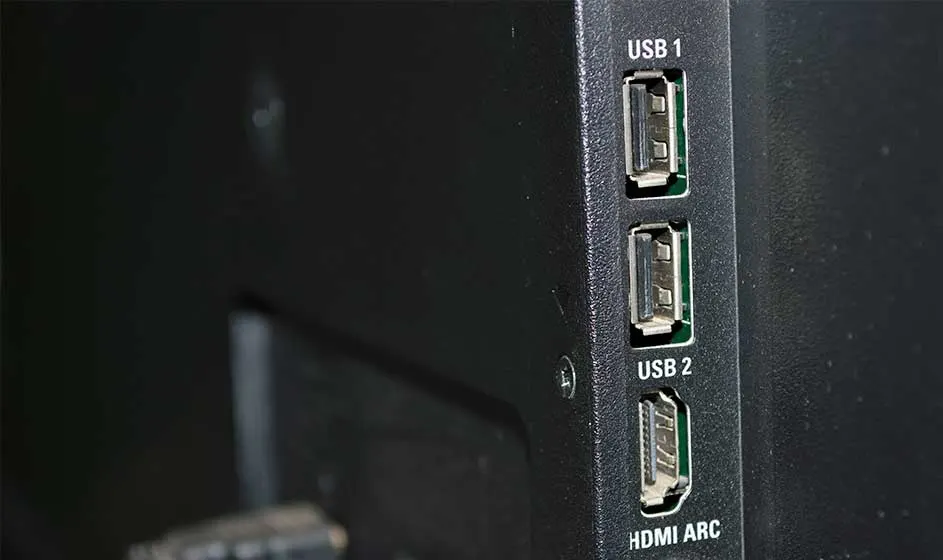 Un appareil noir montre en gros plan deux ports USB et une connexion HDMI ARC sur fond sombre.