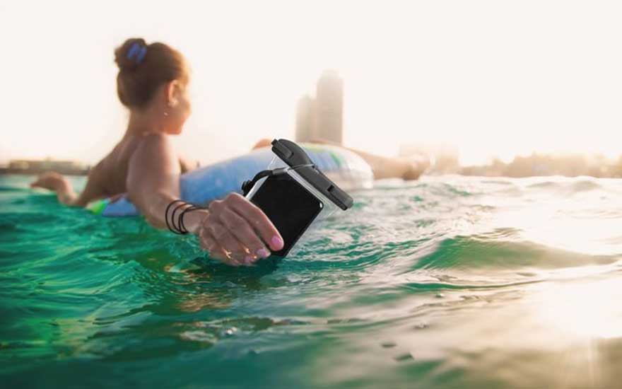 Een persoon dobbert op een opblaasband in het water en houdt een smartphone in een waterdichte hoes stevig vast.