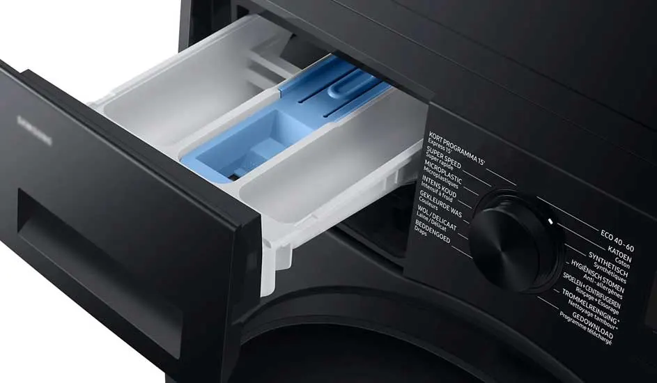 Zwarte wasmachine met open wasmiddellade. De lade is wit met een blauw compartiment. Tekst en knop op de machine.