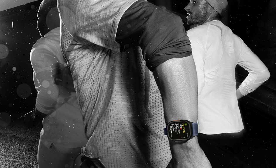 Gros plan sur une montre connectée affichant des données, portée par un individu en tenue de sport, avec d'autres personnes en arrière-plan.