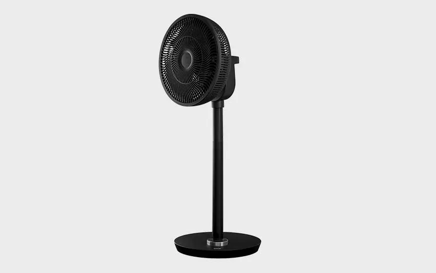 A modern black pedestal fan stands alone against a light background, with a minimalist and sleek appearance.