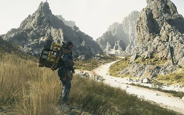 Un voyageur équipé marche dans un paysage montagneux avec rivière, rochers et herbe dorée sous un ciel dramatique.